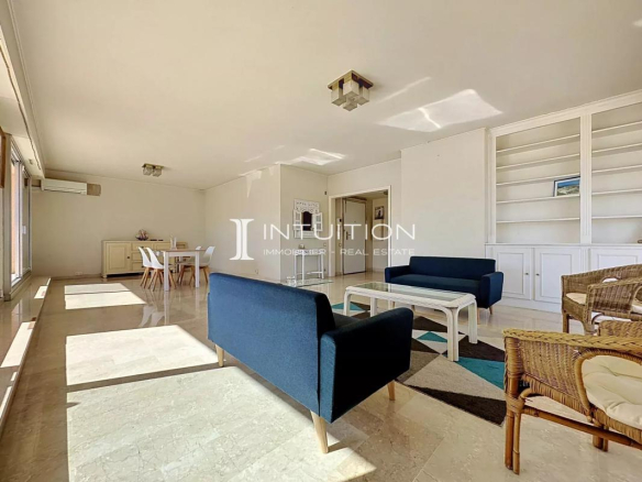 Interior of a spacious apartment with a bright living room, sofas and a dining room.