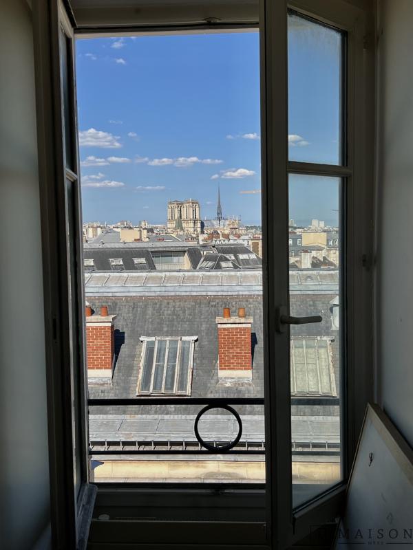 Vue depuis le dernier étage à Paris Vue depuis une fenêtre au dernier étage d'un immeuble à Paris, montrant le toit et des monuments de la ville.