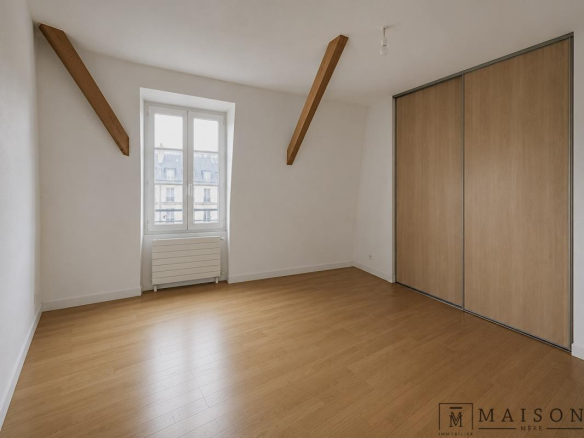 Chambre spacieuse avec parquet et placard intégré, fenêtres donnant sur l'extérieur.