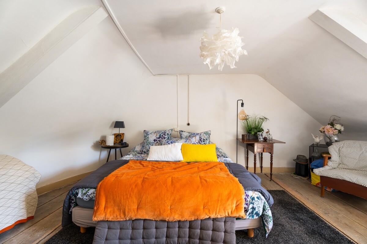 Chambre avec lit et décoration Chambre d'une maison avec lit double, décorée de fleurs et d'un plaid orange.