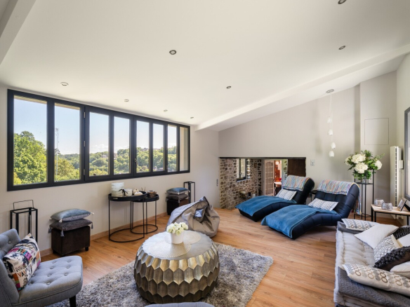 Intérieur d'une maison en pierre avec salon lumineux et vue sur la nature.