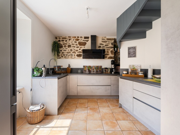 Cuisine moderne dans une maison en pierre avec des murs en pierre apparente et des carreaux en terre cuite.