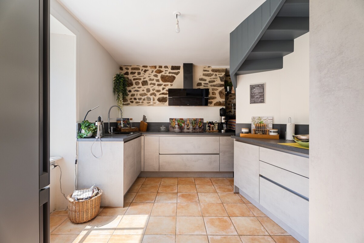 Cuisine d’une maison en pierre à Dinan Cuisine moderne dans une maison en pierre avec des murs en pierre apparente et des carreaux en terre cuite.