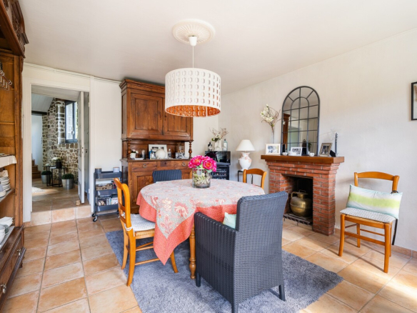 Intérieur d'une maison en pierre avec salle à manger lumineuse et cheminée.