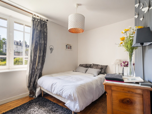 Chambre d'une maison en pierre avec lit double et décoration simple à Dinan.