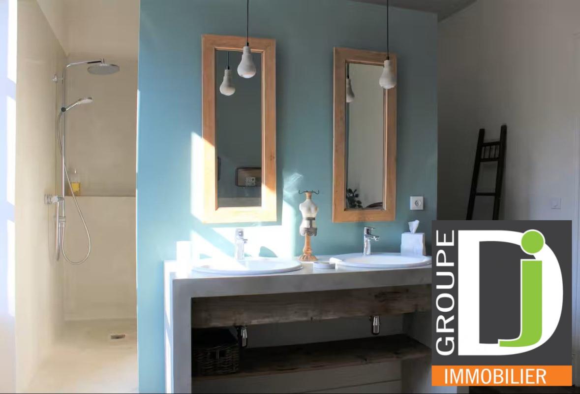 Salle de bain d’une bastide du XIXe siècle Salle de bain moderne avec deux lavabos et douche, murs peints en bleu et beige.