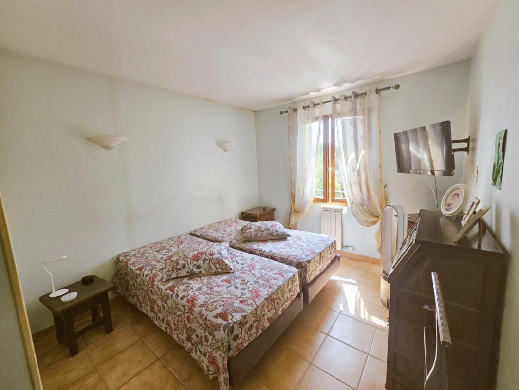 Room with two single beds, window and wall-mounted television.