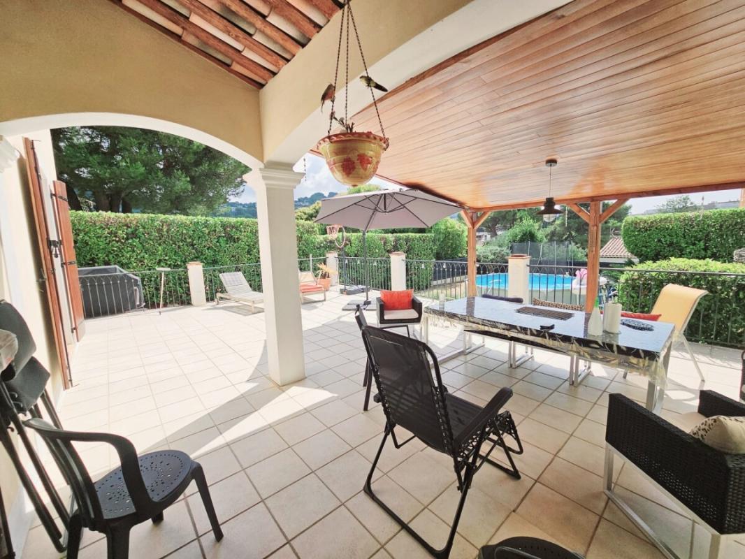 Sunny terrace of a villa with garden furniture and view of the swimming pool.
