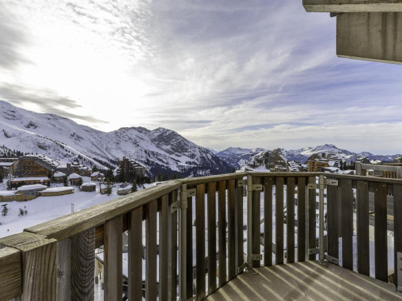 Vue panoramique depuis le balcon d'un penthouse à Avoriaz, avec montagnes enneigées en arrière-plan.