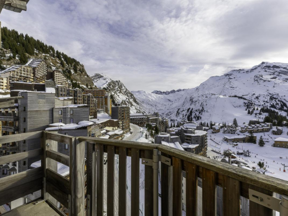 Vue panoramique depuis un balcon d'un penthouse à Avoriaz, avec des montagnes enneigées en arrière-plan.
