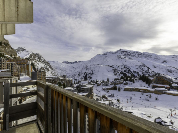 Vue panoramique depuis un balcon d'un penthouse à Avoriaz, avec des montagnes enneigées en arrière-plan.