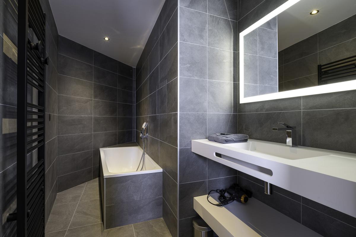 Salle de bain moderne avec baignoire et miroir lumineux dans un penthouse à Avoriaz.