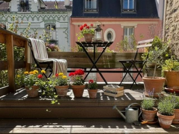 Wooden terrace with flower pots and garden furniture, overlooking colorful houses in Paris.