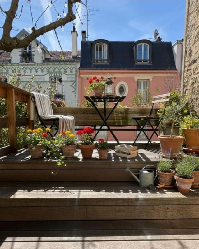 Terrace with views of houses in Paris Wooden terrace with flower pots and garden furniture, overlooking colorful houses in Paris.