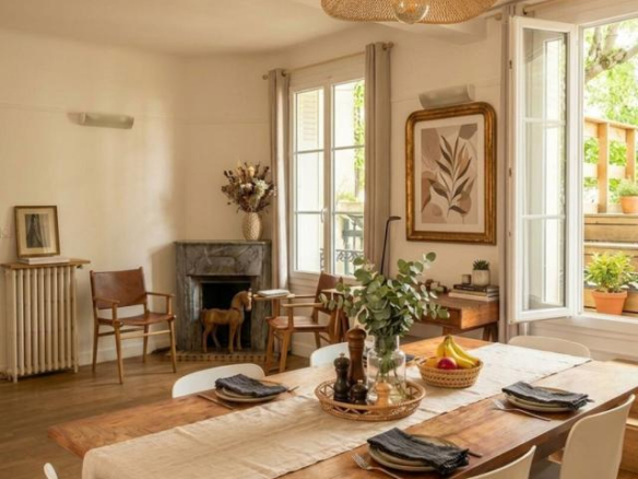 Interior of a house in Paris, dining room with wooden table, white chairs and marble fireplace.