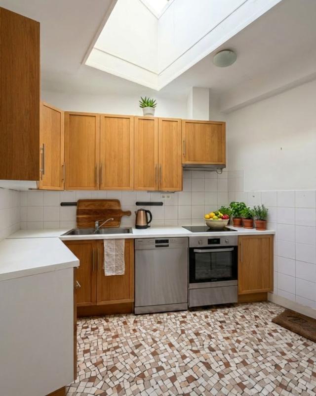 Kitchen of a house in the 13th arrondissement of Paris Modern kitchen with wooden furniture and mosaic floor, lit by a skylight.
