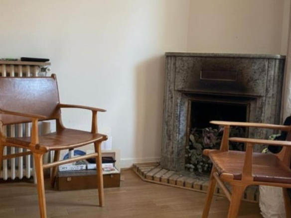 Interior of a house with two wooden chairs and a marble fireplace.