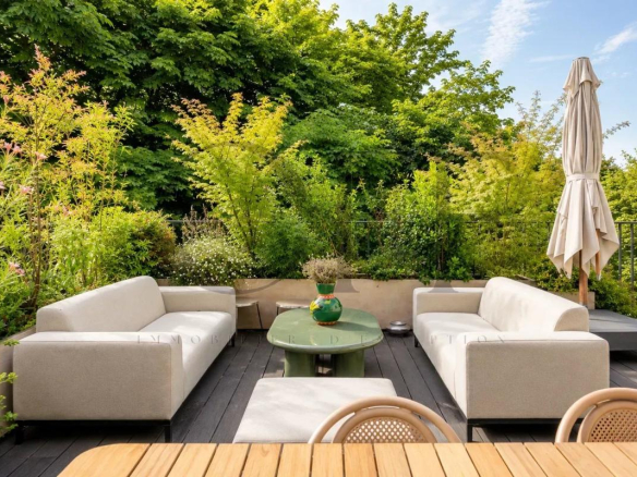 Landscaped terrace of a penthouse in Neuilly-sur-Seine with modern furniture and abundant greenery.