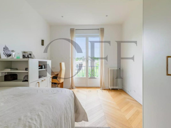 Bright bedroom in a penthouse in Neuilly-sur-Seine, with wooden parquet flooring and a view of the outside.