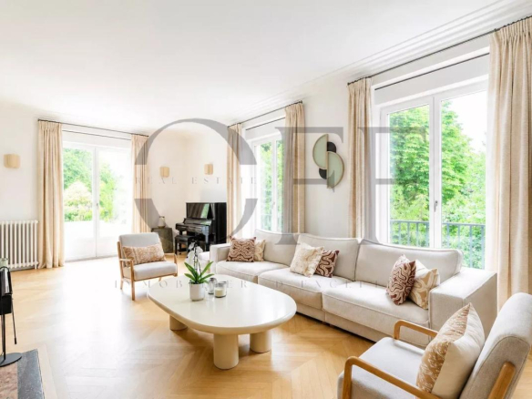 Interior of a duplex penthouse in Neuilly-sur-Seine with a bright living room and windows overlooking a garden.