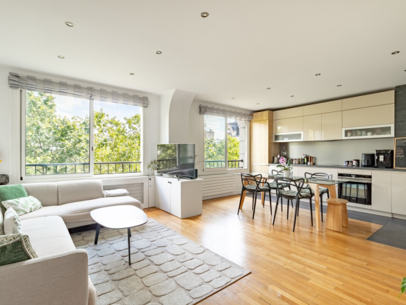 Salon lumineux d'un appartement de 82 m² avec cuisine ouverte et grandes fenêtres à Paris.