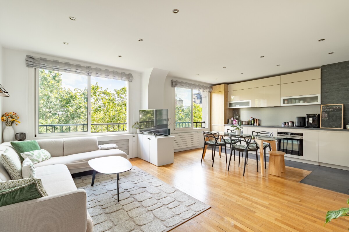 Appartement lumineux à Paris 16ème Salon lumineux d'un appartement de 82 m² avec cuisine ouverte et grandes fenêtres à Paris.