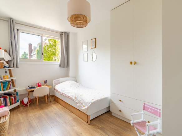 Chambre d'un appartement à Paris avec lit simple et étagère.