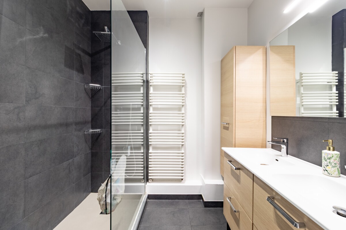Salle de bain d’un appartement à Paris Salle de bain moderne avec douche à l'italienne et meuble vasque en bois.