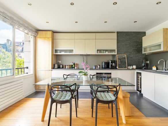 Cuisine moderne avec salle à manger dans un appartement à Paris, fenêtres donnant sur l'extérieur.