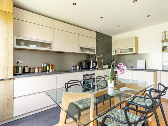 Cuisine moderne avec table à manger en verre et chaises, appartement à Paris 16ème.