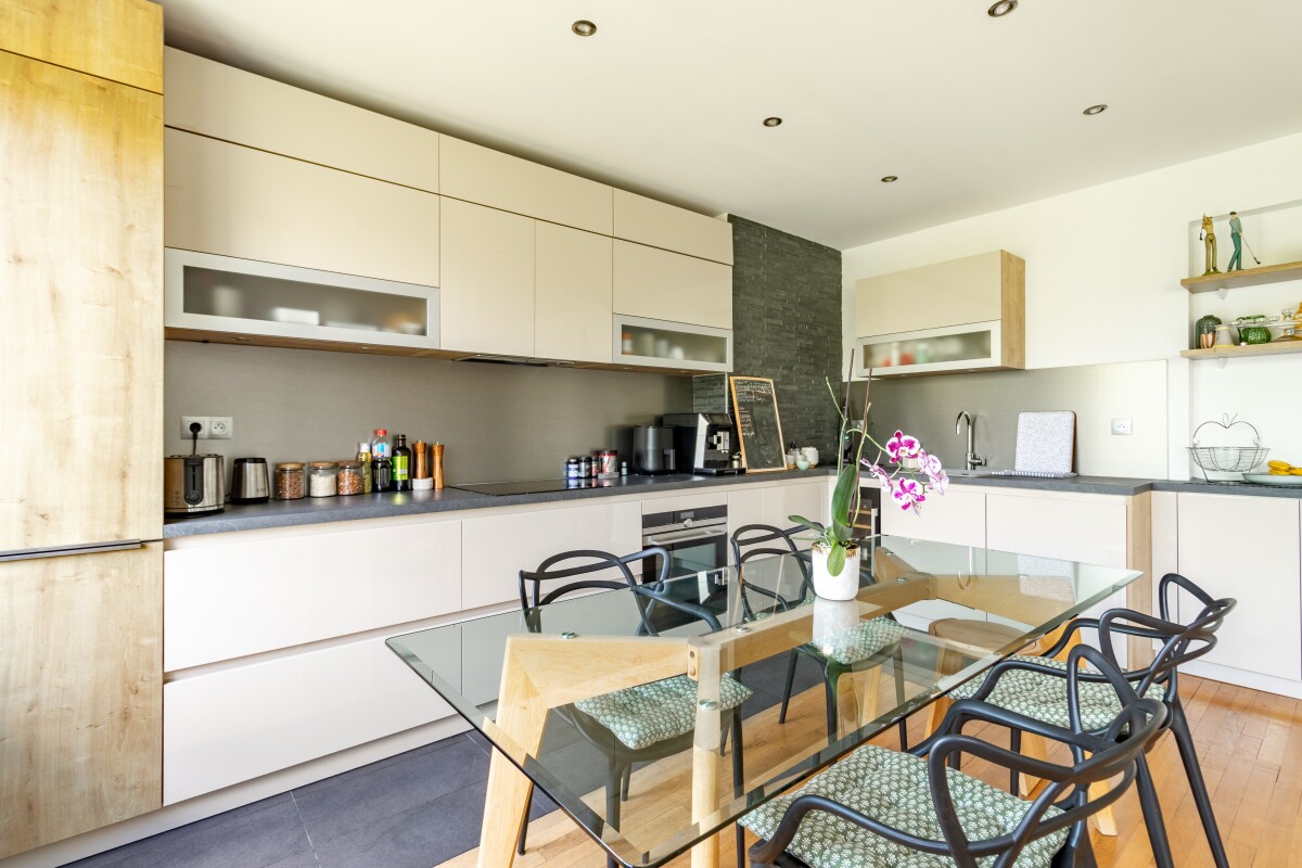 Cuisine d’un appartement à Paris 16ème Cuisine moderne avec table à manger en verre et chaises, appartement à Paris 16ème.