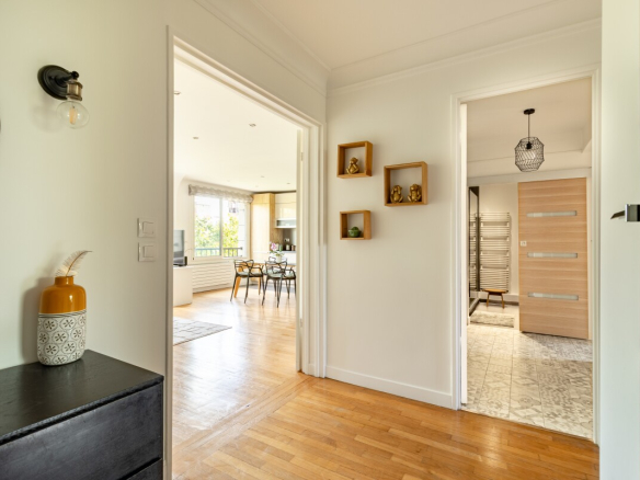 Entrée d'un appartement moderne avec un couloir menant à une pièce de vie lumineuse.