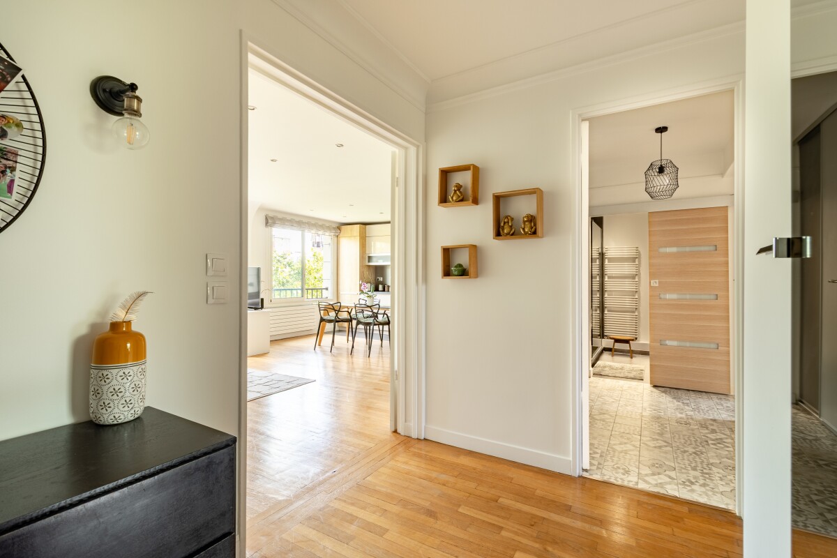 Entrée d’appartement à Paris 16ème Entrée d'un appartement moderne avec un couloir menant à une pièce de vie lumineuse.