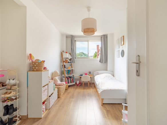 Chambre d'appartement à Paris 16ème avec lit, étagère et fenêtres.