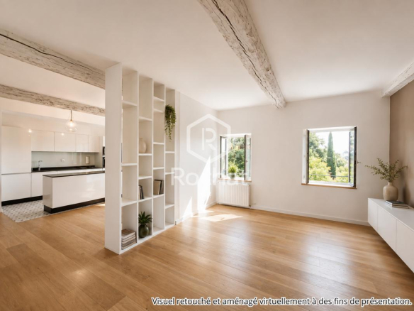 Intérieur d'une maison rénovée avec des murs clairs et des poutres apparentes, vue sur l'extérieur.