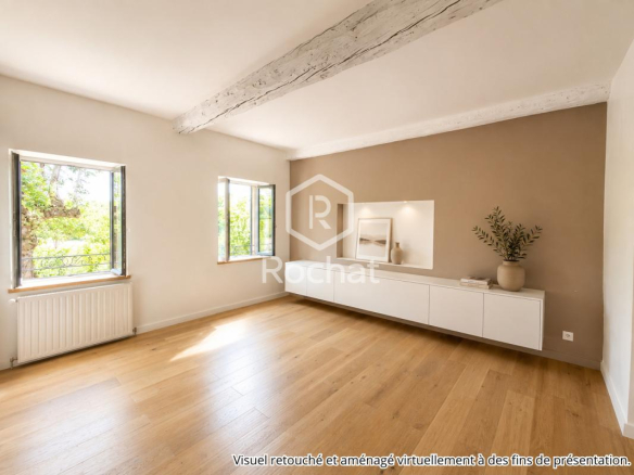 Intérieur d'une maison rénovée avec murs clairs et parquet, fenêtres donnant sur l'extérieur.