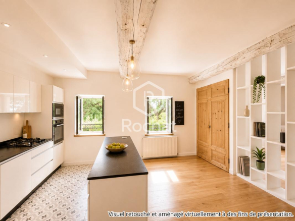 Cuisine moderne avec îlot central et fenêtres donnant sur l'extérieur dans une maison rénovée.