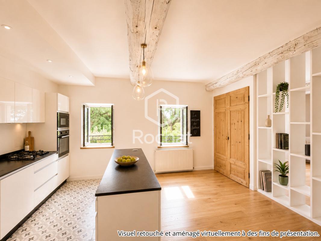 Cuisine d’une maison rénovée à Curis-au-Mont-d’Or Cuisine moderne avec îlot central et fenêtres donnant sur l'extérieur dans une maison rénovée.
