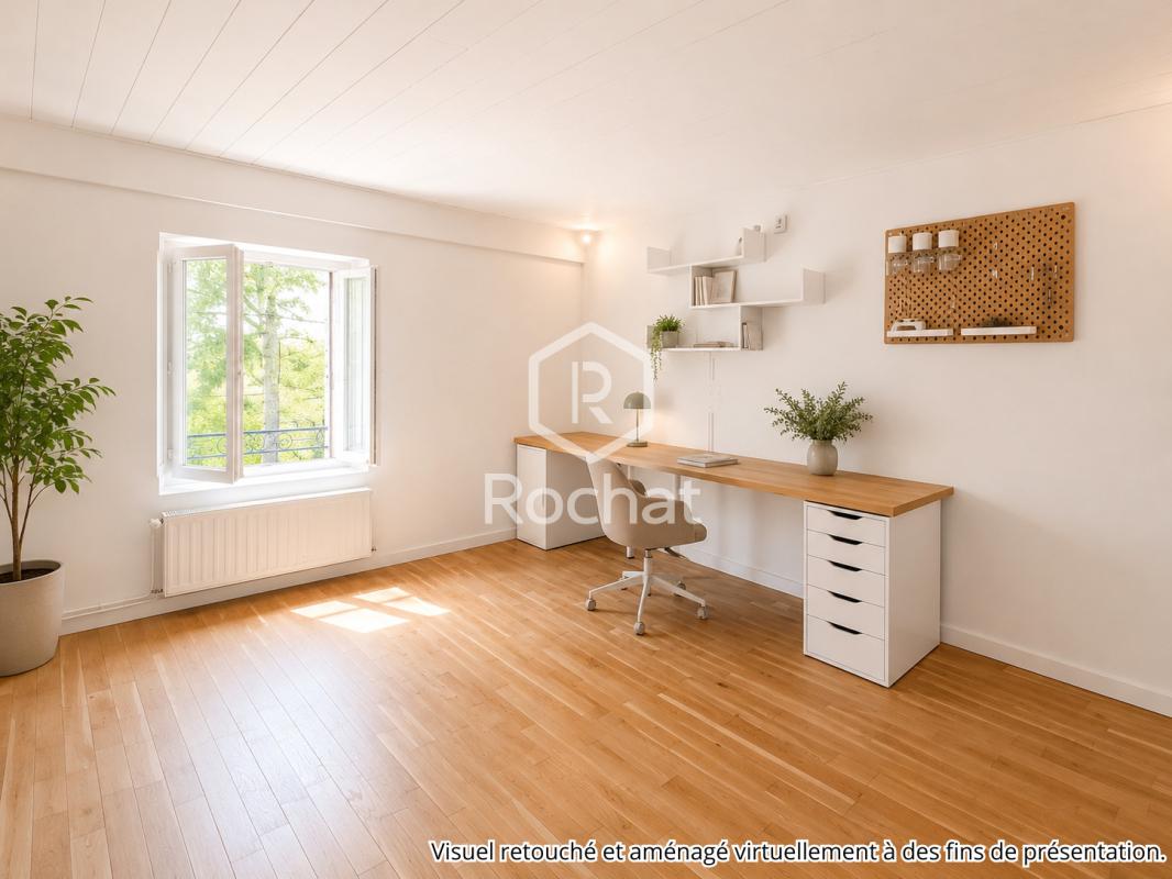 Bureau rénové dans une maison à Curis-au-Mont-d’Or Bureau lumineux avec parquet en bois et fenêtre, décoré de plantes et mobilier moderne.