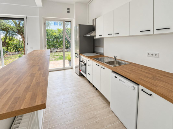 Cuisine moderne et lumineuse d'un appartement avec accès au jardin.