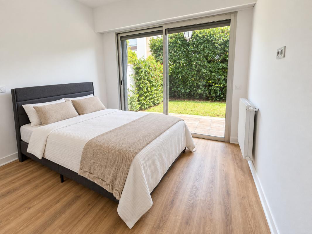 Chambre avec accès au jardin Chambre d'un appartement avec accès direct à un jardin, sol en bois et grandes fenêtres.