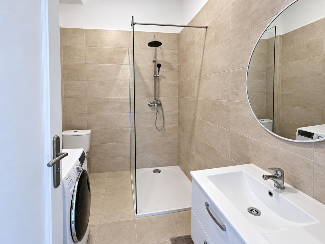 Salle de bain moderne Salle de bain moderne avec douche à l'italienne, meuble lavabo et machine à laver.