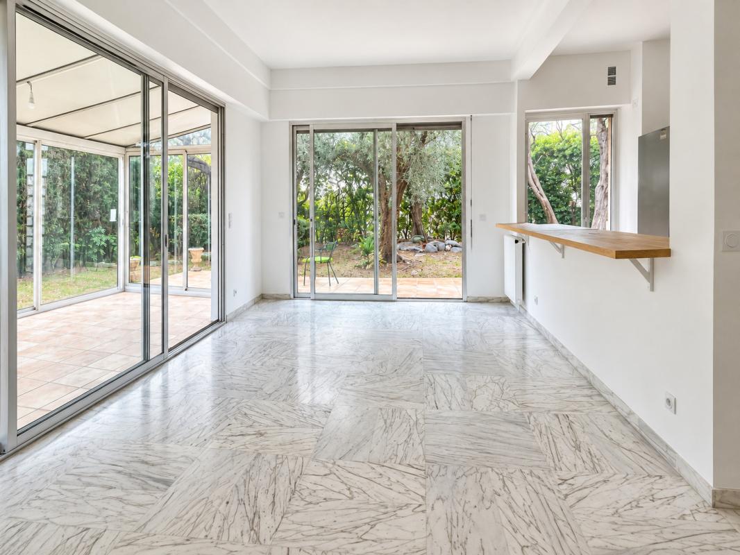 Appartement 4 pièces avec jardin à Nice Intérieur d'un appartement de 4 pièces avec véranda et accès à un jardin arboré.