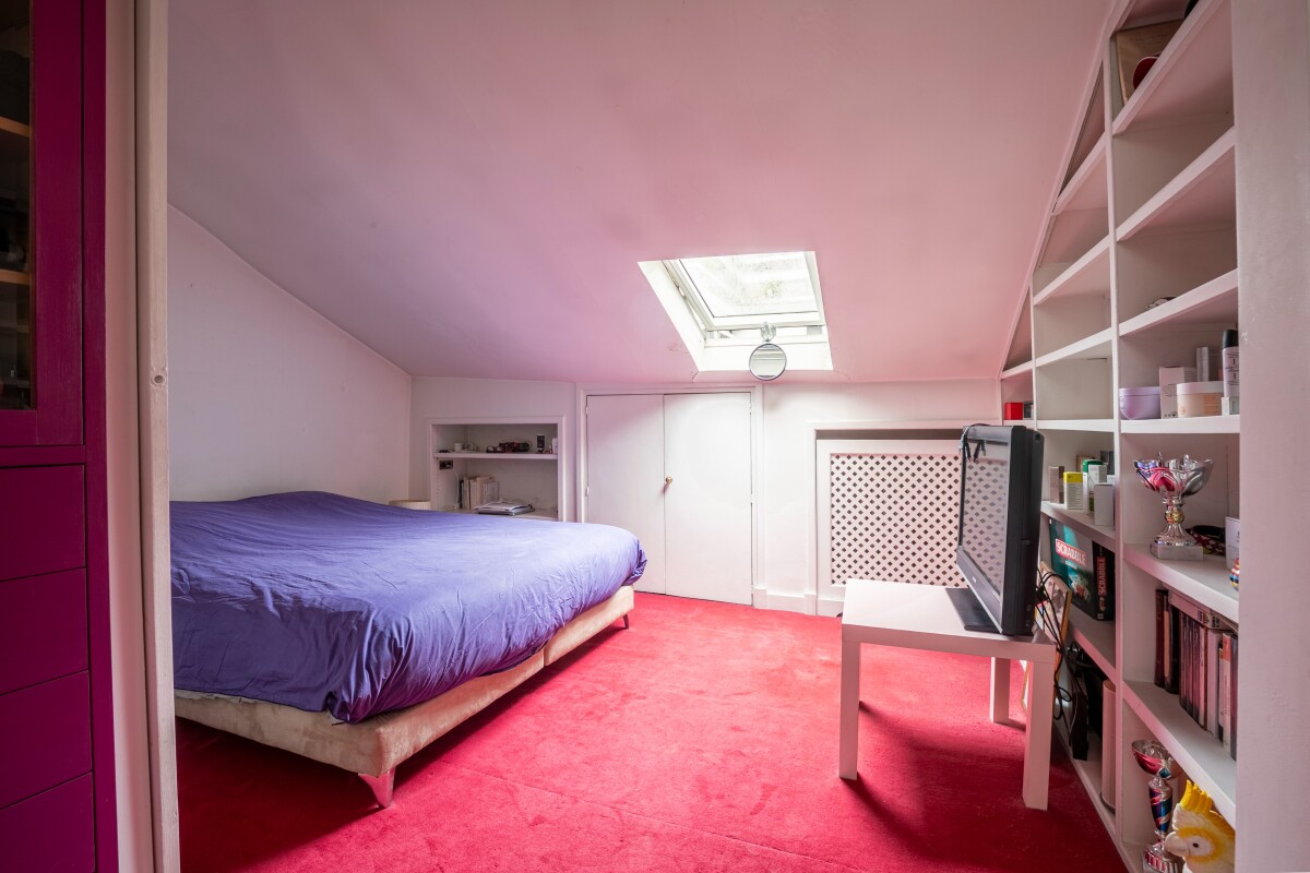 Chambre d'un atelier d'artiste en triplex à Paris, avec un lit et une fenêtre de toit.