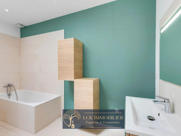 Salle de bain moderne avec baignoire et lavabo, murs verts et beige.