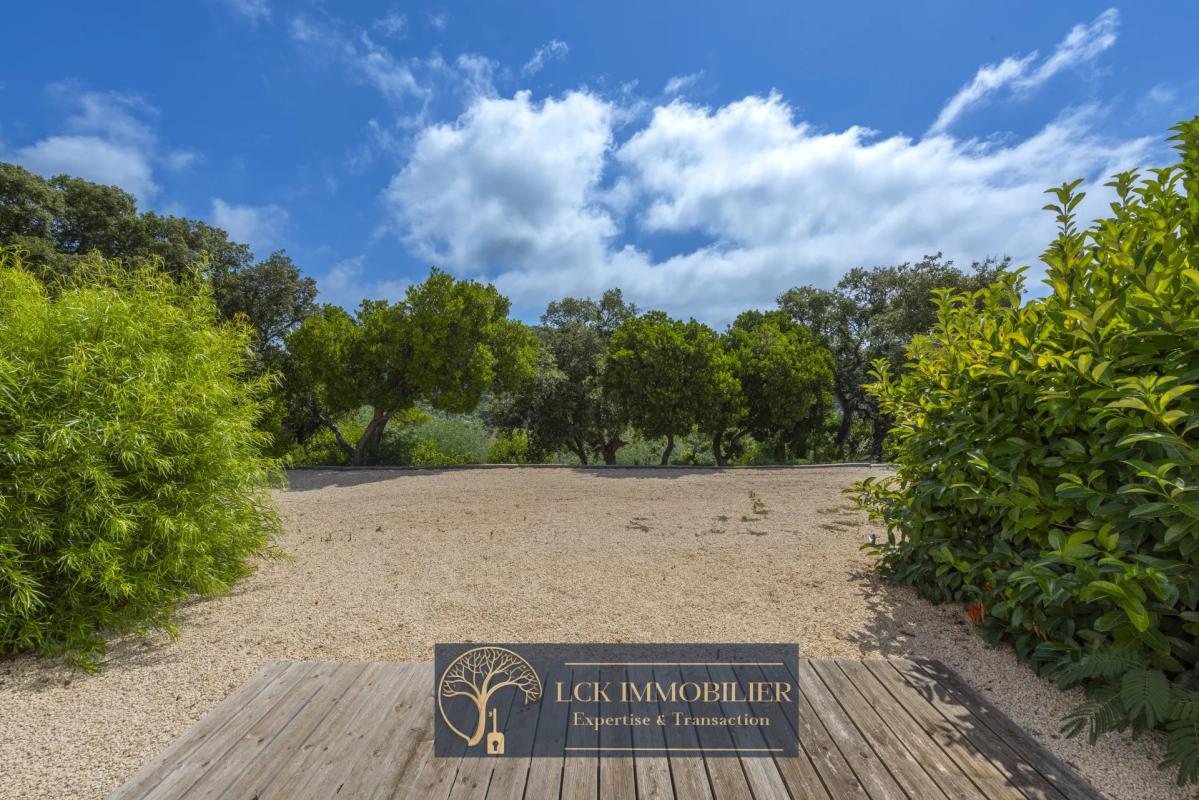 Jardin de la villa à Roquebrune-sur-Argens Vue d'un jardin arboré avec une terrasse en bois, entouré d'arbres, à Roquebrune-sur-Argens.