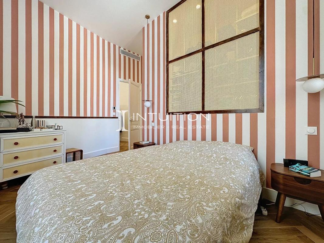 Chambre d’appartement bourgeois à Antibes Chambre d'un appartement bourgeois à Antibes avec des murs rayés et un lit.