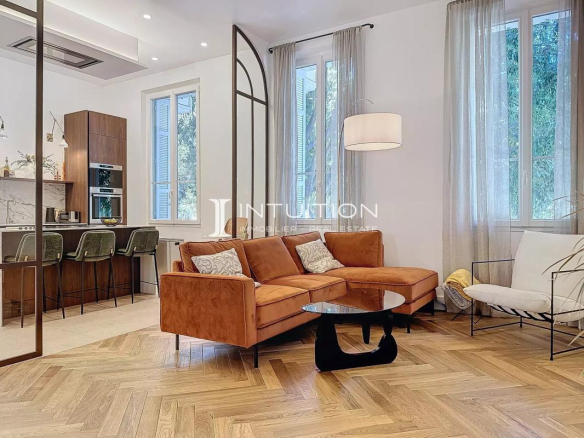 Salon d'un appartement bourgeois à Antibes avec canapé et cuisine ouverte.