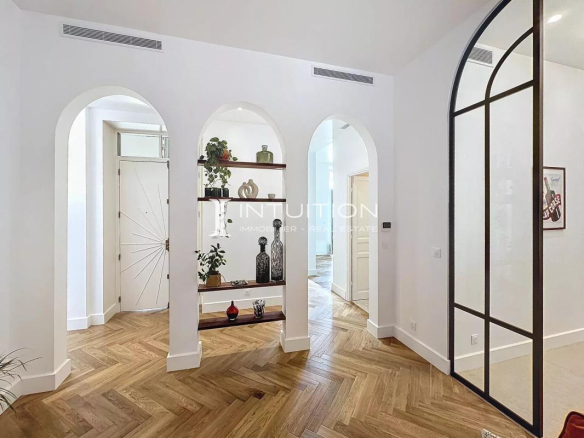 Entrée d'un appartement bourgeois à Antibes avec arches et parquet en bois.