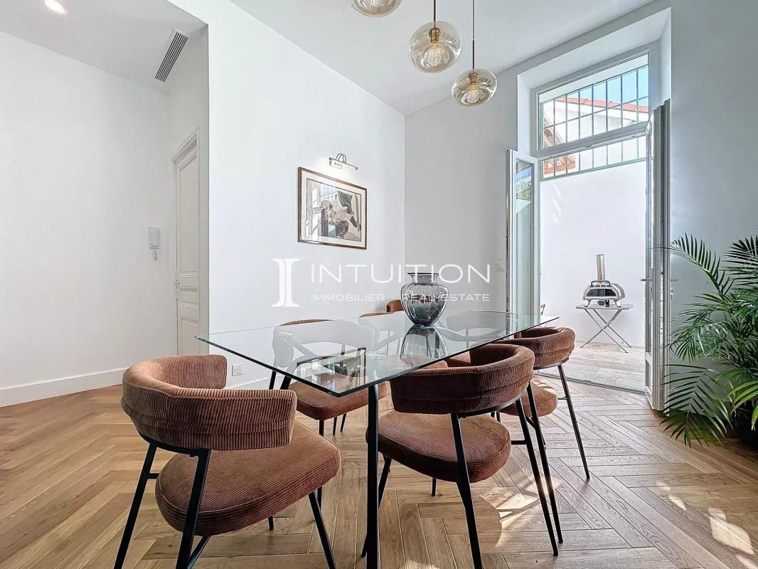 Appartement bourgeois à Antibes Salle à manger d'un appartement bourgeois à Antibes avec table en verre et chaises en velours.
